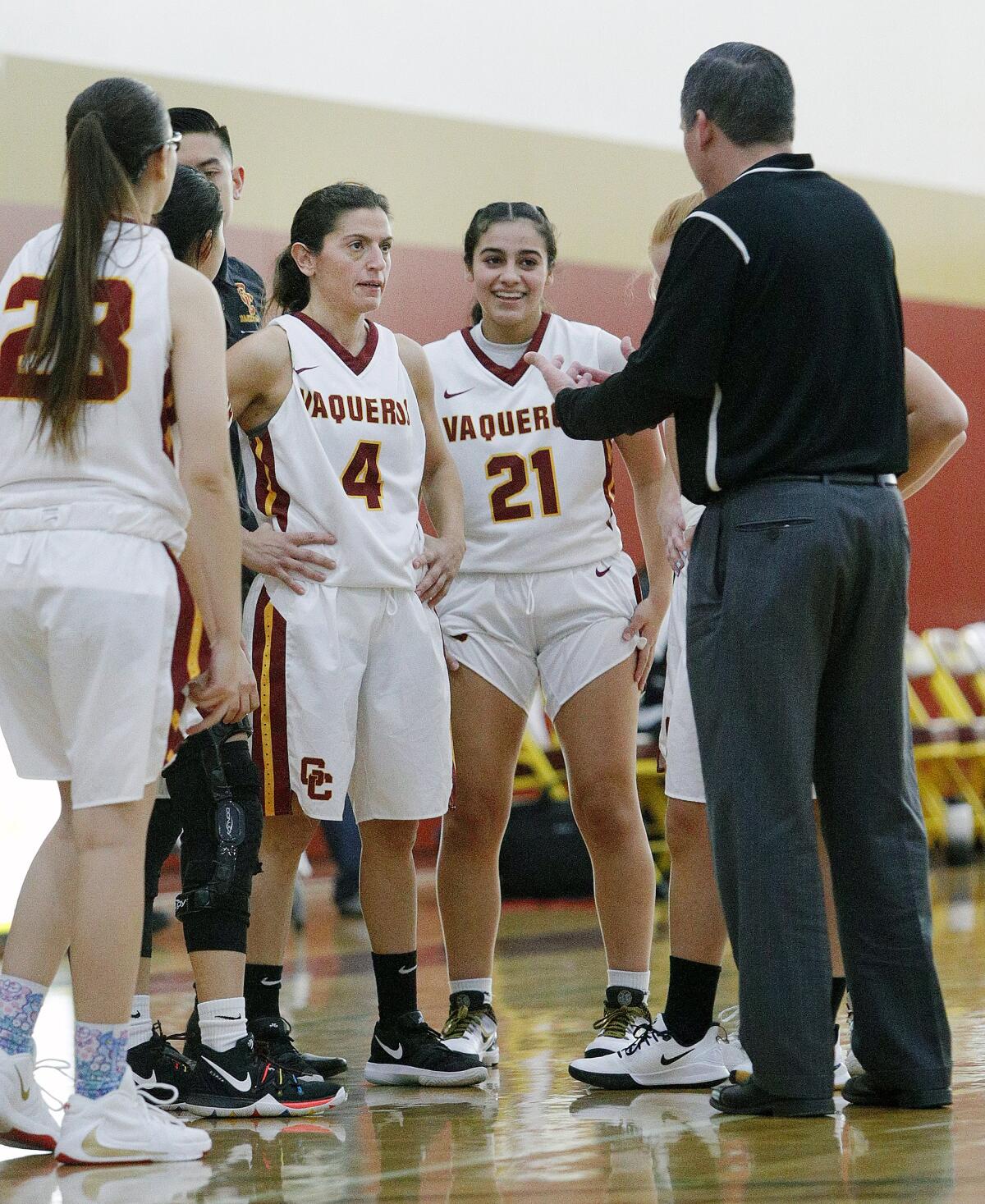 Glendale Community College's Vicky Oganyan, center, takes instructions from Glendale Community College's head coach Joel Weiss during a timeout against Allan Hancock in a women's basketball game in the annual Vaquero basketball tournament at Glendale Community College on Wednesday, December 18, 2019. Oganyan is the long-time head coach of the Burroughs High School girls' basketball team and is playing for GCC while taking classes at GCC. Glendale won the game to improve to 10-1 on the season by defeating Allan Hancock 58-50.