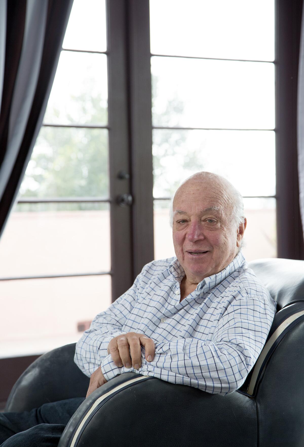 Seymour Stein sits in a chair and smiles