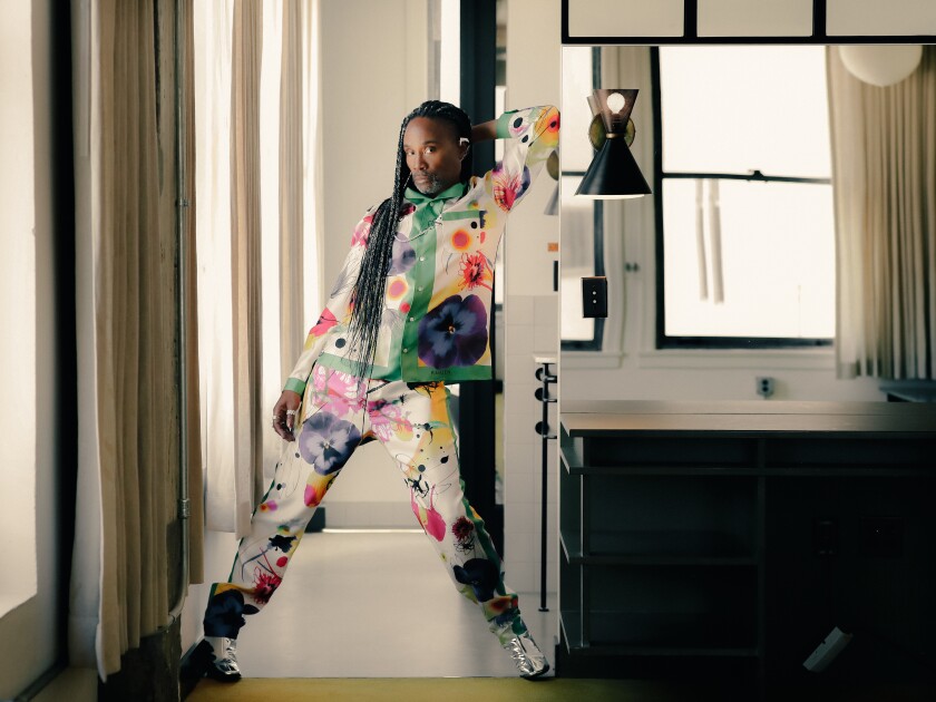 Billy Porter in a colorful floral outfit photographed in a hotel room.
