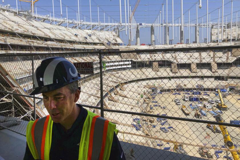 Los Angeles Rams chief operating officer Kevin Demoff speaks to reporters on the south concourse above the bowl of the NFL stadium rising in Inglewood, Calif., Tuesday, July 30, 2019. The multi-billion-dollar complex is on schedule to open in July 2020. Officials from the NFL, the Rams and the Los Angeles Chargers toured the stadium as part of early preparations for the Super Bowl in February 2022. (AP Photo/Greg Beacham)