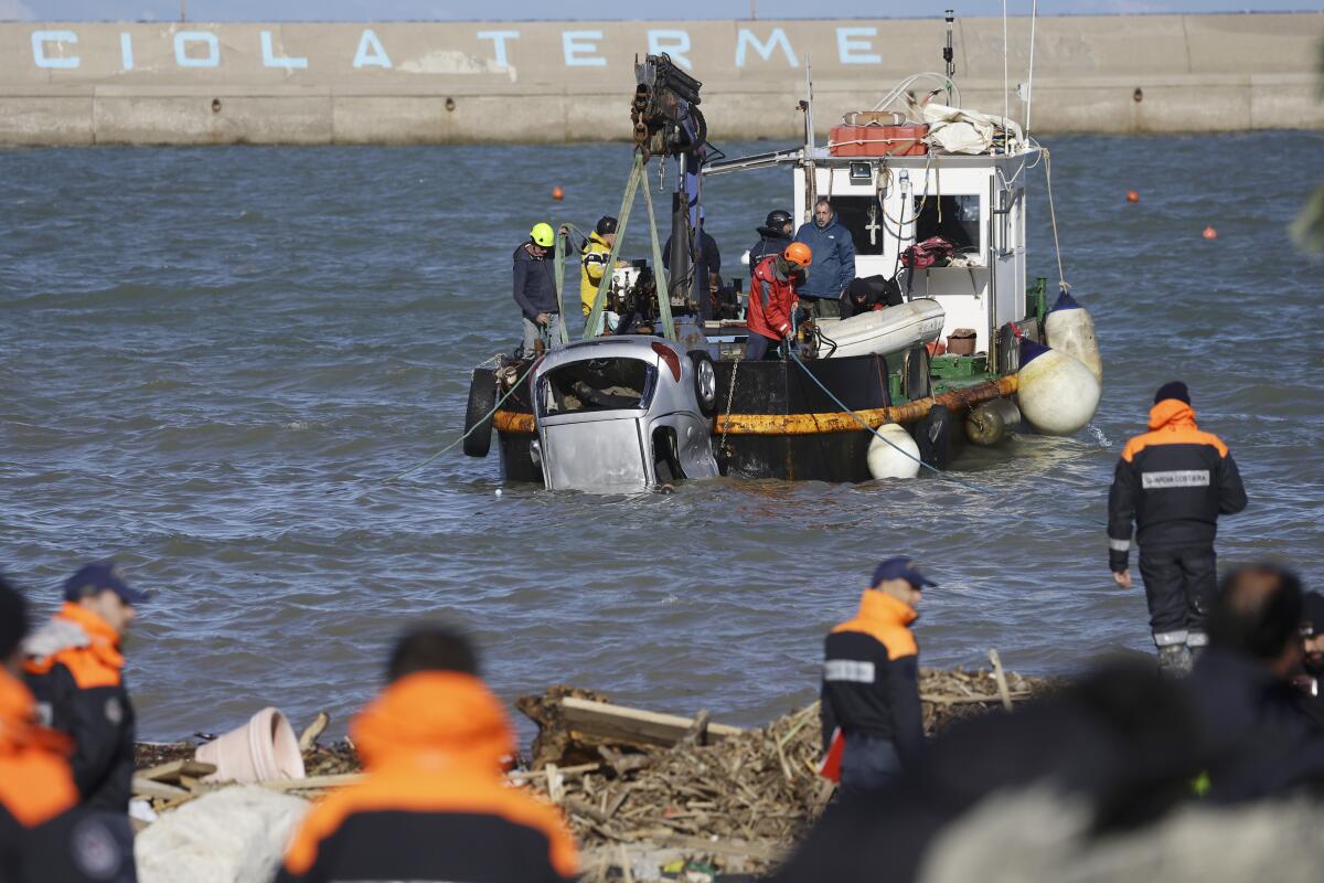 Rescuers on a boat pull a damaged car from the sea.