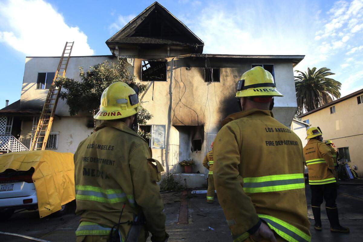 Firefighters survey fire damage to an Echo Park apartment building in which two people were found dead.