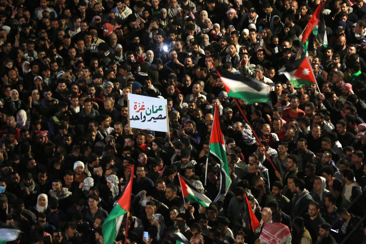 A huge crowd of people, some holding black, white, green and red flags.