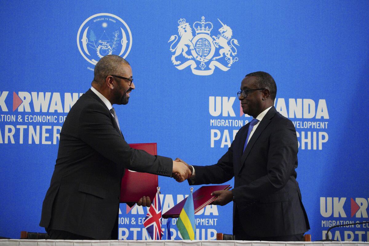 British Home Secretary James Cleverly, left, and Rwandan Minister of Foreign Affairs Vincent Biruta shake hands.