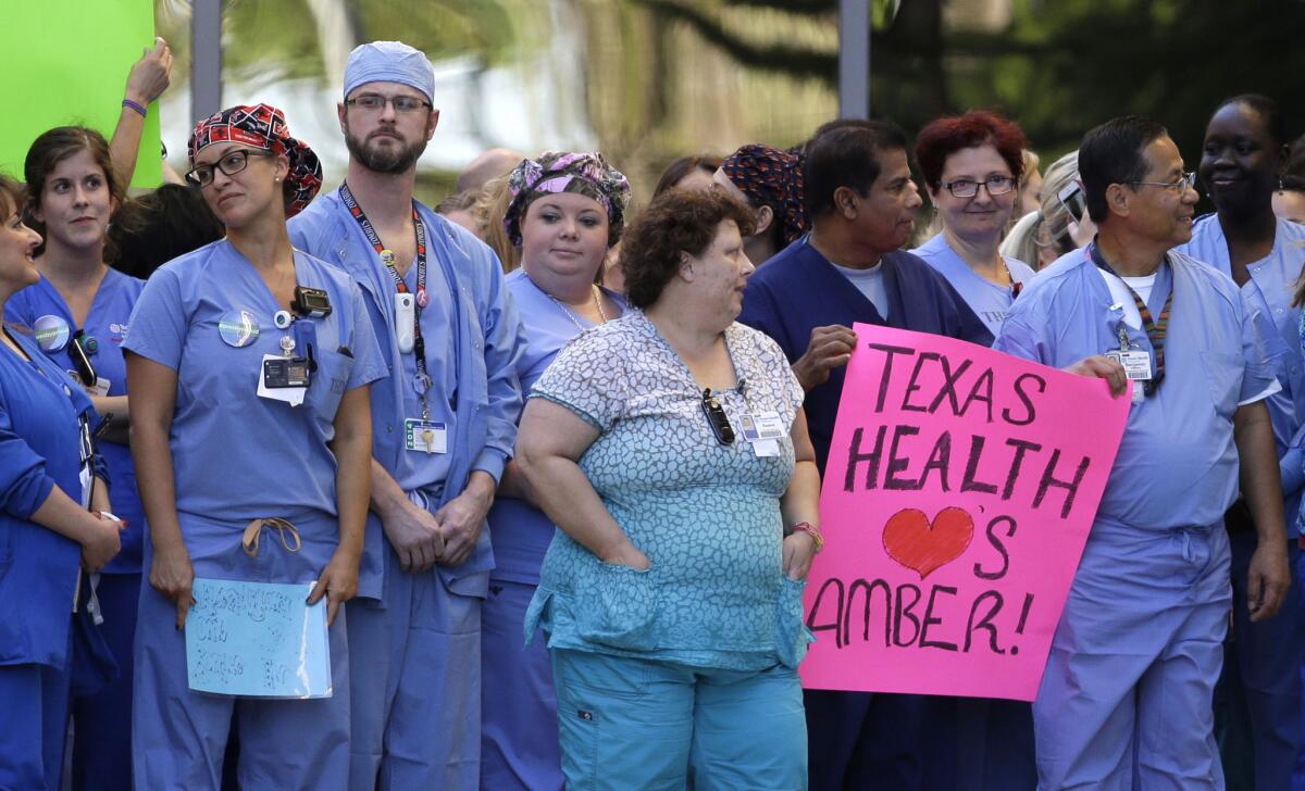 Workers at Texas Health Presbyterian Hospital in Dallas assemble Thursday. One holds a sign supporting nurse Amber Vinson, who contracted Ebola after treating a patient there.