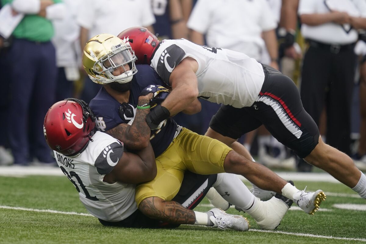 Notre Dame's Kyren Williams (23) is tackled by Cincinnati's Curtis Brooks (92) and Joel Dublanko (41) during the first half of an NCAA college football game, Saturday, Oct. 2, 2021, in South Bend, Ind. (AP Photo/Darron Cummings)