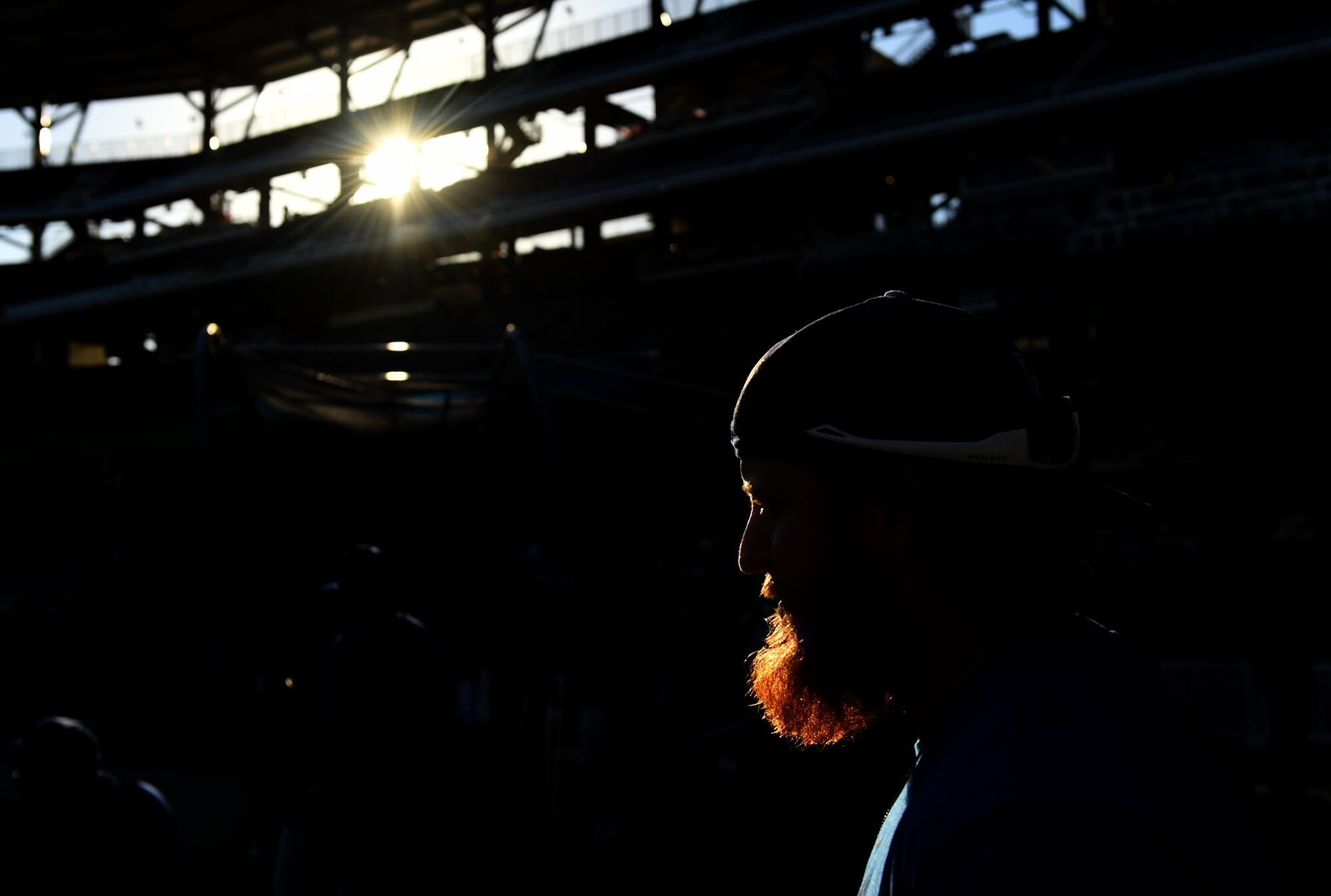 A man with a beard in a baseball hat is covered in shadow.