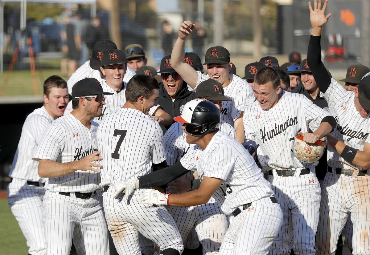 Huntington Beach's Bradley Navarro (7) is mobbed by teammates after hitting a walk-off home run to defeat Corona del Mar. 