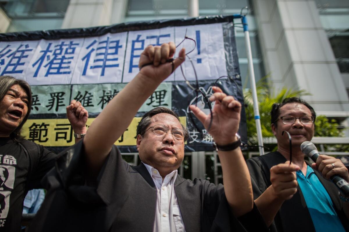 Hong Kong Democratic Party's Albert Ho (C) releases himself from mock hand cuffs as he and legislator Leung Kwok-hung (L), known as "Long Hair", attend a protest in Hong Kong on July 12, 2015, after at least 50 Chinese human rights lawyers and activists were detained or questioned in recent days in an "unprecedented" police swoop, rights groups said on July 11.