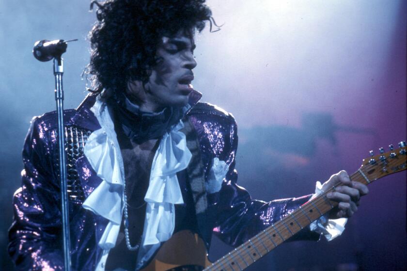 Wearing a ruffled shirt and shiny purple jacket, Prince performs at the Forum on Feb. 19, 1985 in Inglewood.