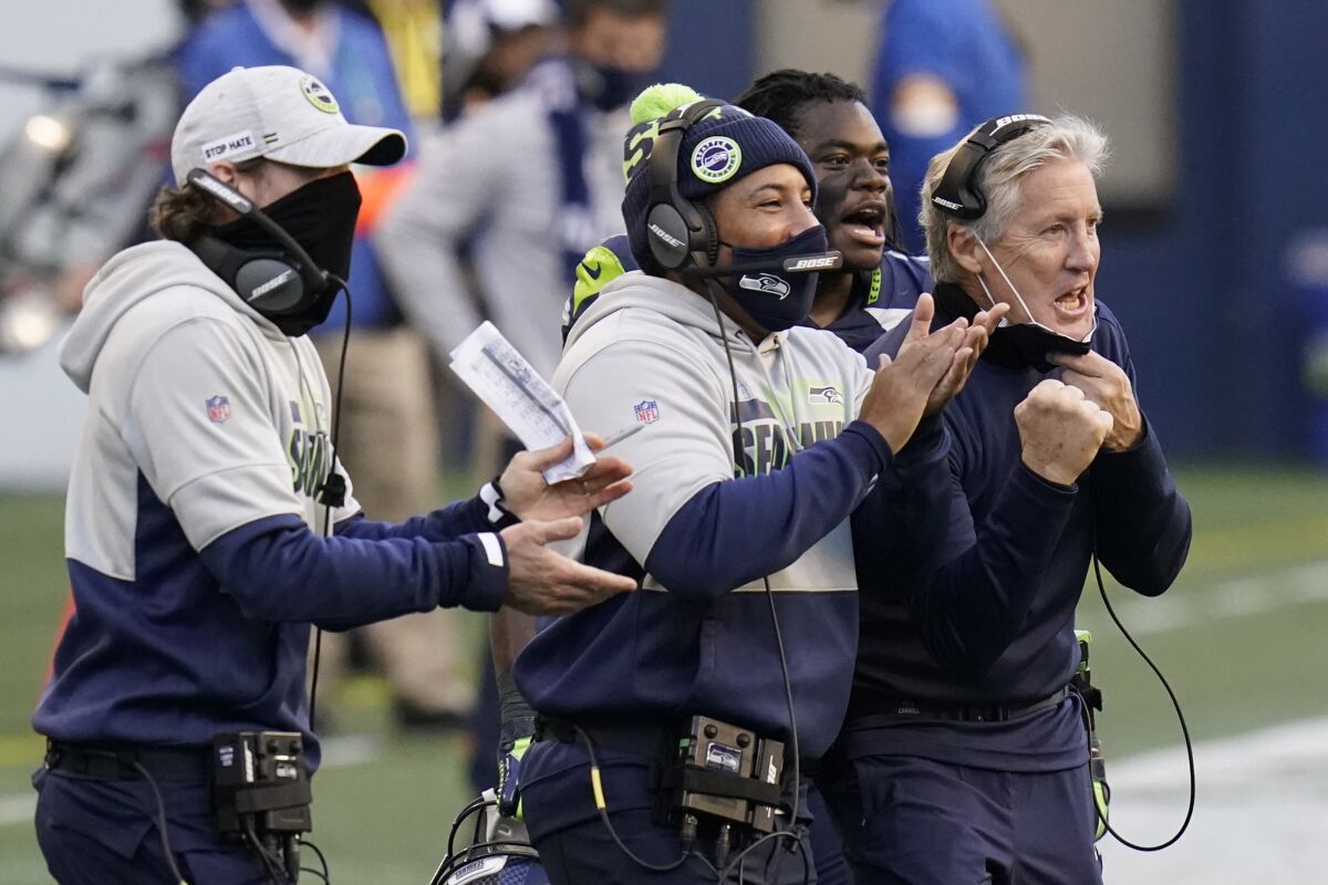 Seattle Seahawks head coach Pete Carroll, right, reacts with running back DeeJay Dallas, second from right, and other coaches after a play against the San Francisco 49ers during the second half of an NFL football game, Sunday, Nov. 1, 2020, in Seattle. (AP Photo/Elaine Thompson)