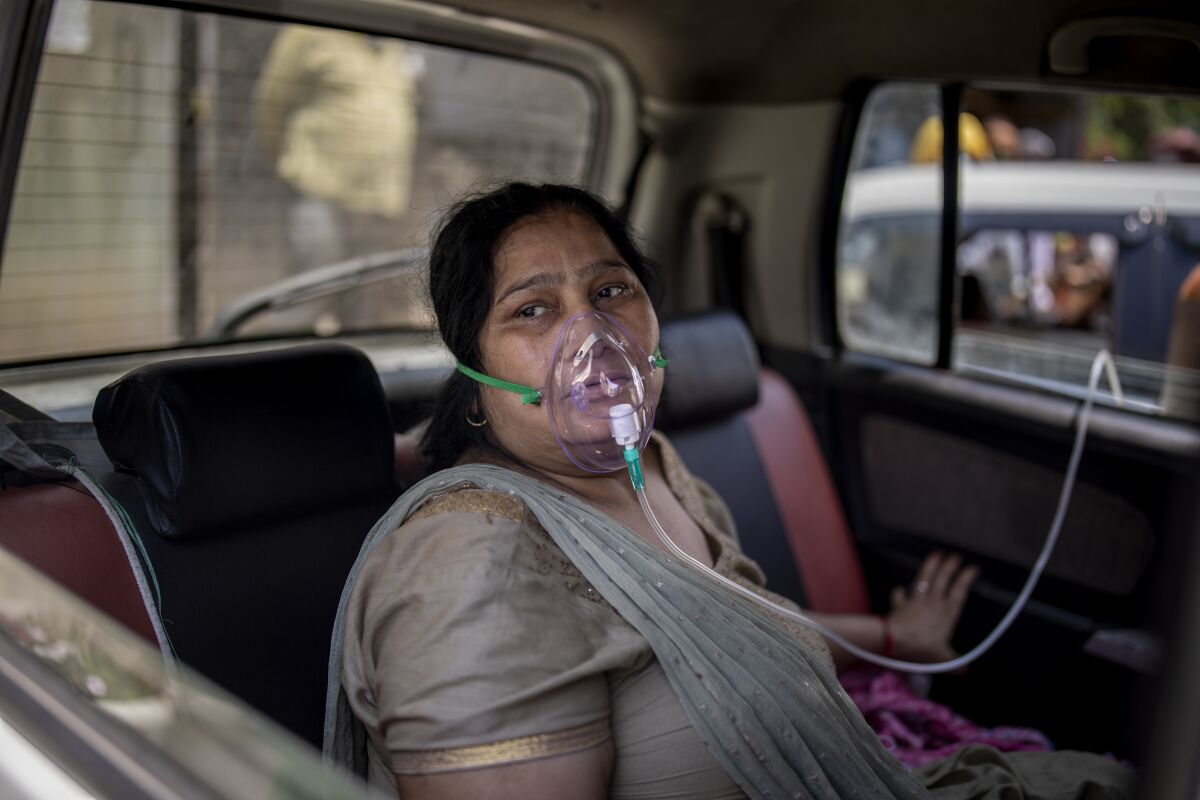 A COVID-19 patient sits inside a car with an oxygen mask.