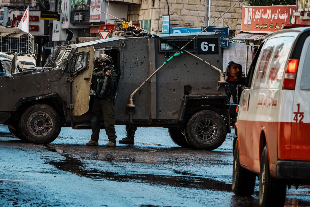 Israeli soldiers stop and inspect ambulances traveling on Al Mahata street as Israeli forces conduct raid operations.