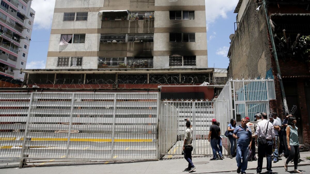 An armed drone used in what the Venezuelan government says was an attempt on the life of President Nicolas Maduro crashed Saturday into an apartment complex in Caracas, causing a fire. Reporters gather outside the complex Sunday.