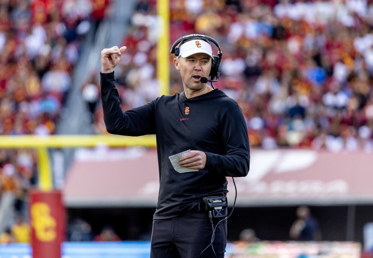 USC coach Lincoln Riley signals up field while holding a card that contains the Trojans' offensive plays.