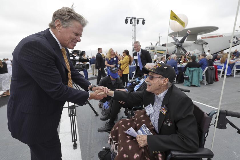 SAN DIEGO, CA - JUNE 4, 2022: President and CEO of the USS Midway Museum Mac McLaughlin shakes hands with Battle of Midway veteran Aviation Radioman First Class Charles Monroe, 98, before the start of the commemoration ceremony of the 80th anniversary of the Battle of Midway and the Centennial of U.S. Navy Aircraft Carriers at the USS Midway Museum in San Diego on Saturday, June 4, 2022. (Hayne Palmour IV / For The San Diego Union-Tribune)