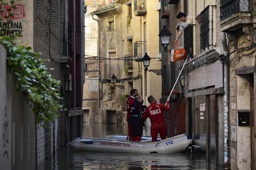 A rescue team help a woman in her home in a flooded area near the Ebro River in Tudela, northern Spain, Sunday, Dec. 12, 2021. Heavy rain has led to flooding in northern Spain. (AP Photo/Alvaro Barrientos)