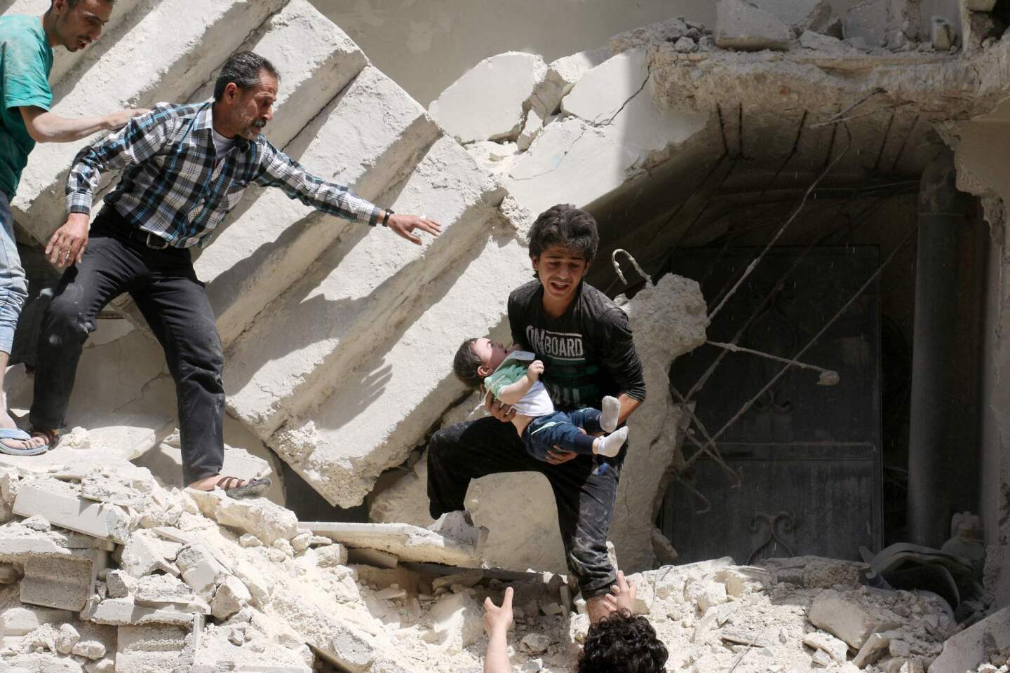 Syrians evacuate a toddler from a destroyed building after an airstrike on the rebel-held Kalasa neighborhood in the northern Syrian city of Aleppo.