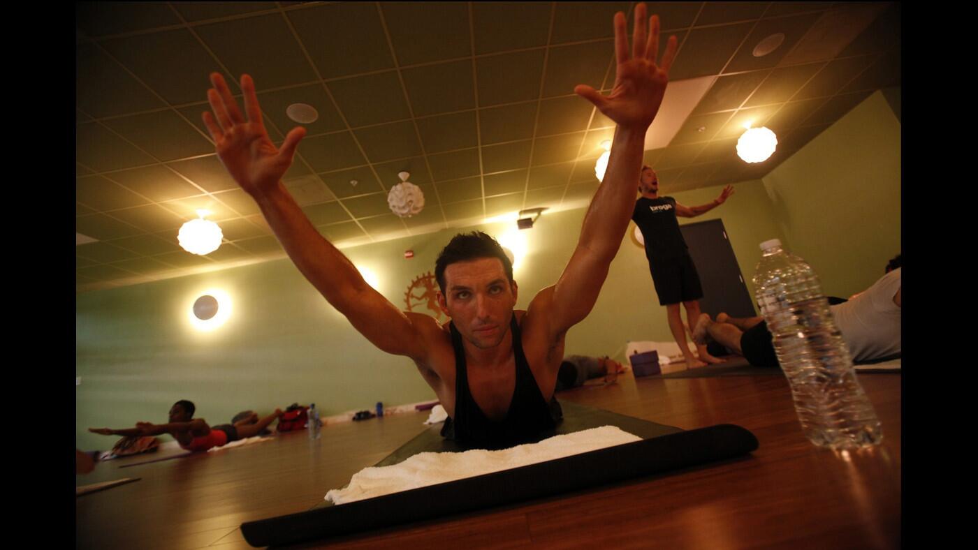 Robert Sidoti, standing, leads a Broga Yoga class at Crunch in West Hollywood. Broga Yoga is a blend of vinyasa-style yoga, body-weight based functional fitness movements and high-intensity interval training which also substitutes rock music for chanting.