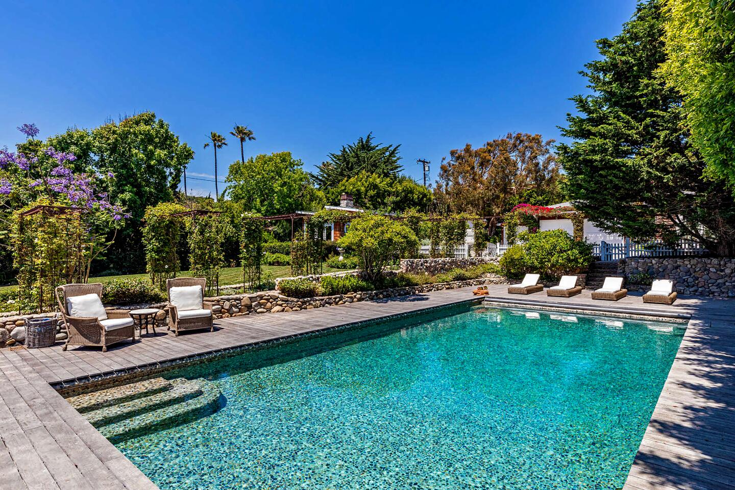 This coastal Cape Cod overlooks the ocean from a bluff in Point Dume, descending to a stretch of private beach.