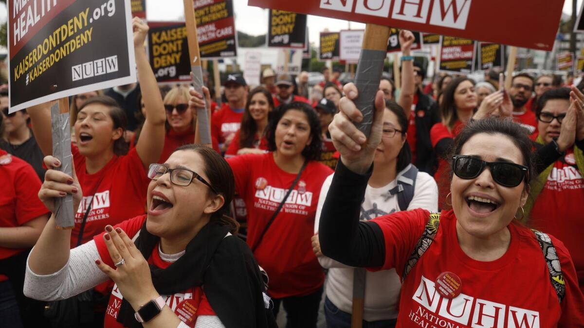 Marriage and family therapists Leslie Fuentes-Nguyen, left, and Monica Garcia rally with other mental health workers outside the Kaiser hospital on Sunset Boulevard in Los Angeles on Monday.