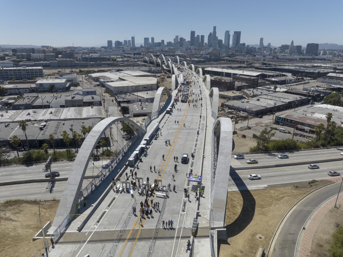 An aerial view of people walking on the Sixth Street Viaduct, with downtown Los Angeles in the distance