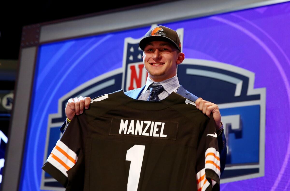 Johnny Manziel holds up his jersey after being selected by the Cleveland Browns.