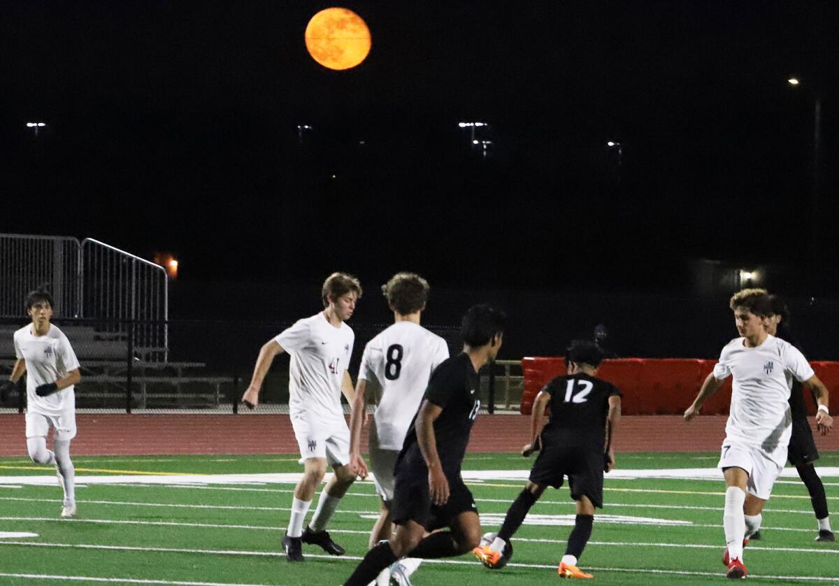 Los Amigos midfielder Eduardo Reyes (12) dribbles around Laguna Beach defenders during a nonleague match on Tuesday.