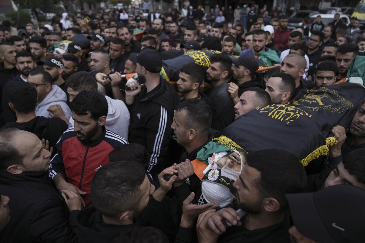 Mourners carrying the bodies of three slain Palestinians
