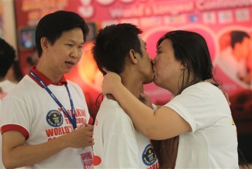 A judge, left, talks to competitors Ekkachai Tiranarat, center, and Laksana Tiranarat during the World's Longest Continuous Kiss Competition in Pattaya, southeastern Thailand, Thursday, Feb. 14, 2013. The event was held in an attempt to break the Guinness world record and to celebrate Valentine's Day. (AP Photo/Sakchai Lalit)