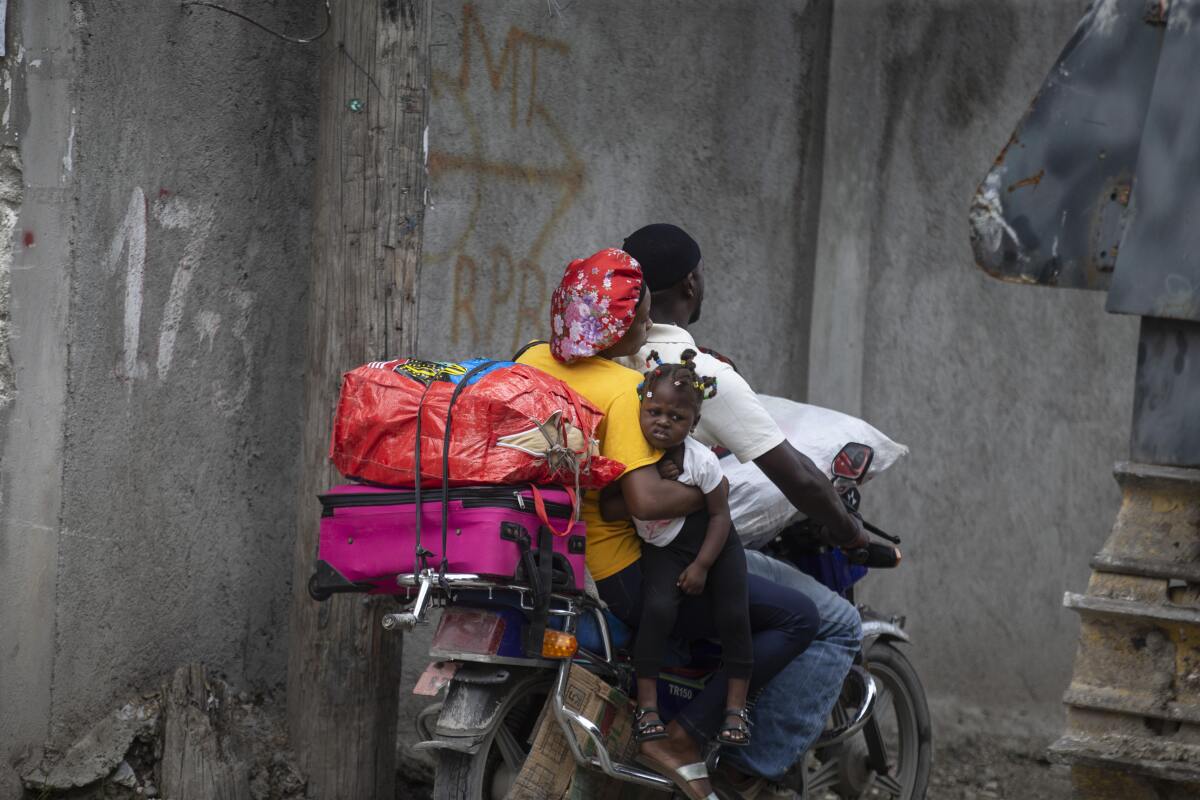 Residents travel on a motorbike as they flee their home.
