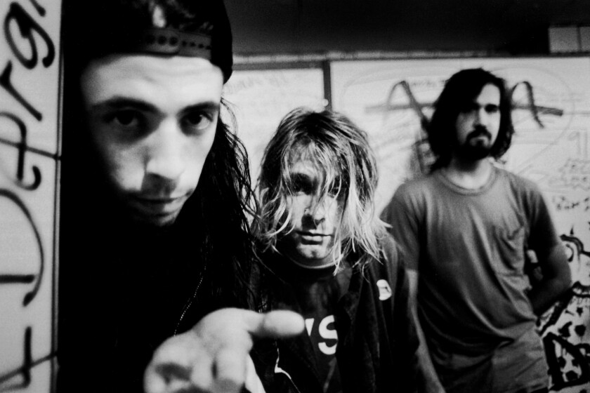 A black and white photo of three shaggy rock musicians in 1991