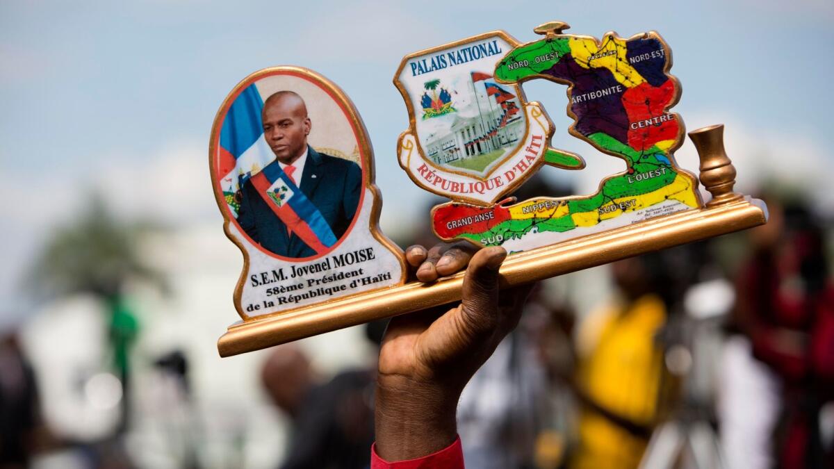 During the inauguration ceremony in Port-au-Prince on Feb. 7, 2017, a supporter of Haiti's new President Jovenel Moise holds up his portrait along with Haiti's map and an image of the National Palace before it was destroyed.