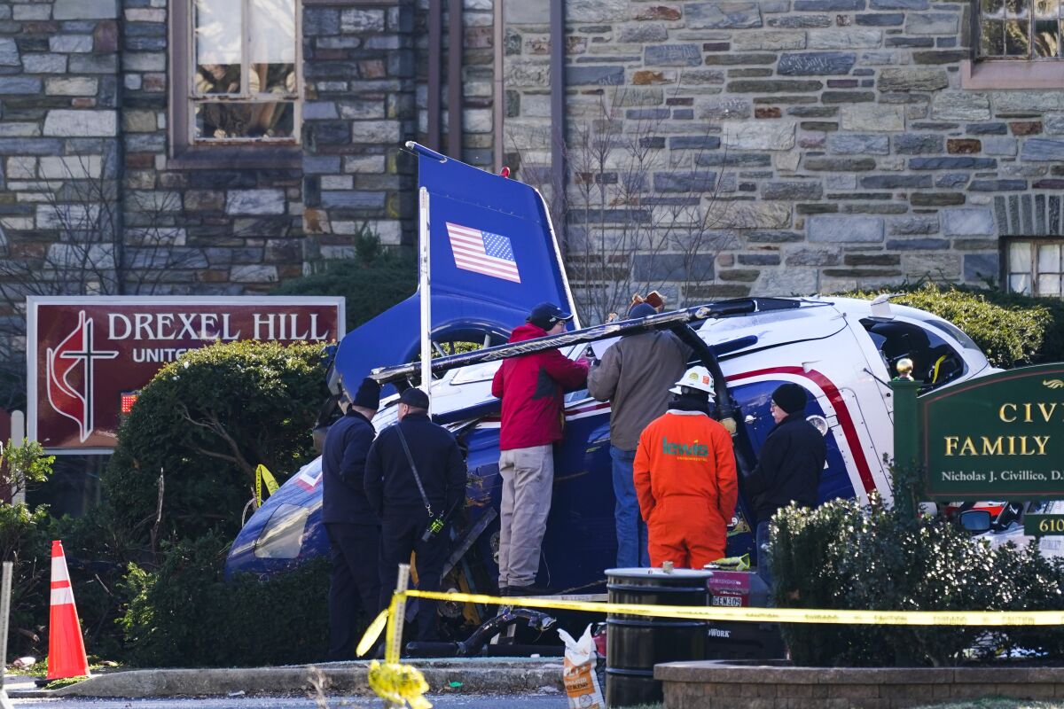 A medical helicopter rests next to the Drexel Hill United Methodist Church after it crashed in the Drexel Hill section of Upper Darby, Pa., on Wednesday, Jan. 12, 2022. Authorities and a witness say a pilot crash landed a medical helicopter without casualties in a residential area of suburban Philadelphia, miraculously avoiding a web of power lines and buildings as the aircraft fluttered, hit the street and slid into bushes outside a church.(AP Photo/Matt Rourke)