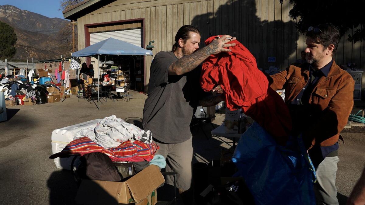 Volunteer Jason Estrada, left, receives donated items, including bed sheets from Eric Cheevers of Los Angeles at the Upper Ojai Relief Center.