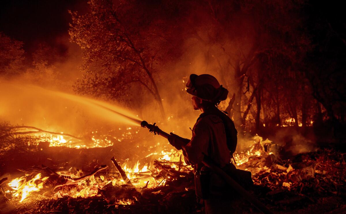 A firefighter sprays a hose on a wildfire