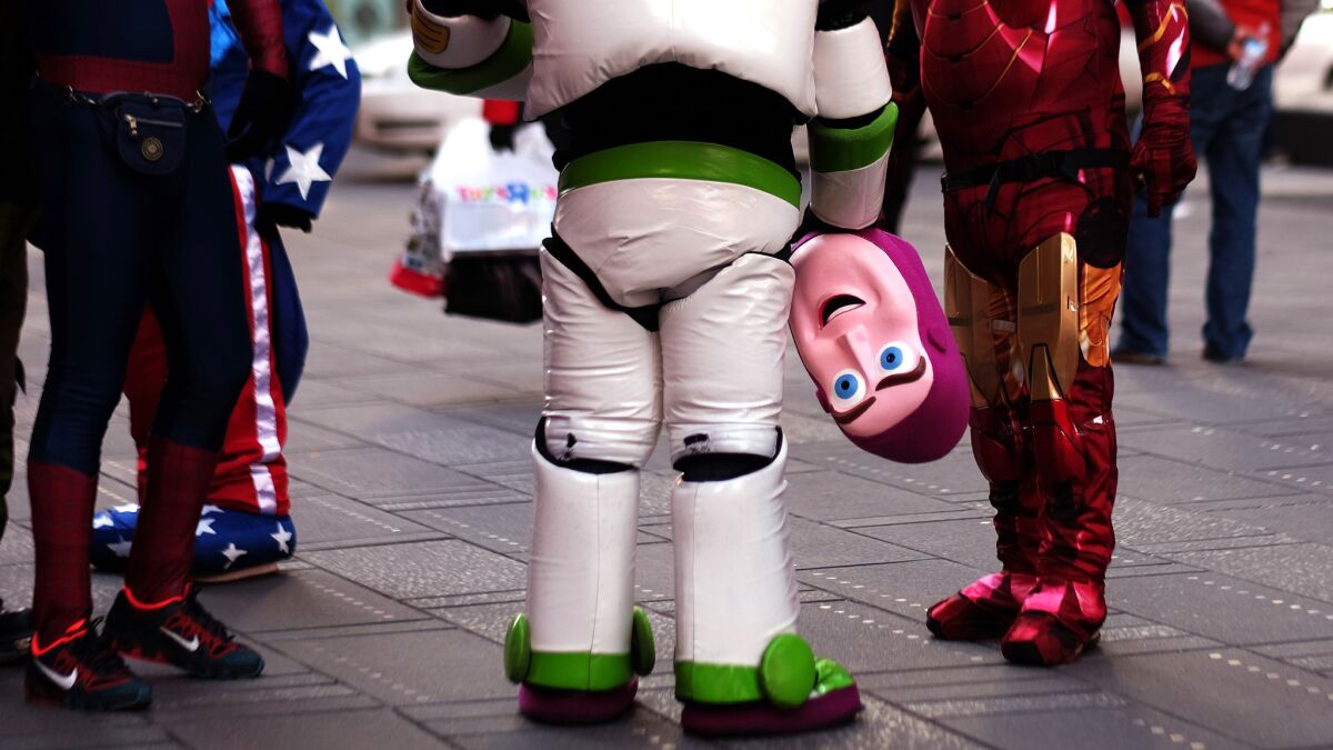 "Buzz Lightyear" holds his mask while standing with other costumed superheroes and cartoon characters at Times Square in 2015