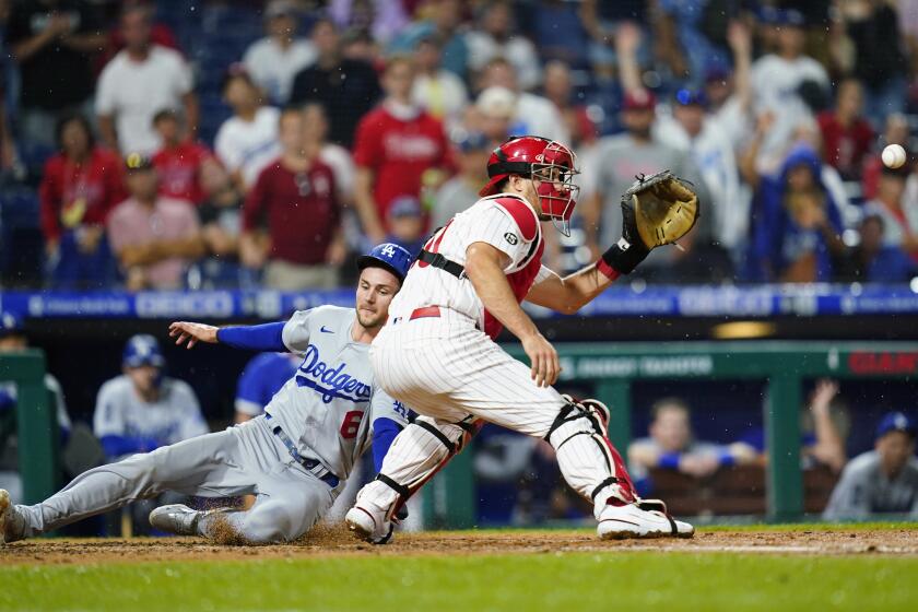 The Dodgers' Trea Turner slides past Phillies catcher J.T. Realmuto on Aug. 10, 2021, in Philadelphia.