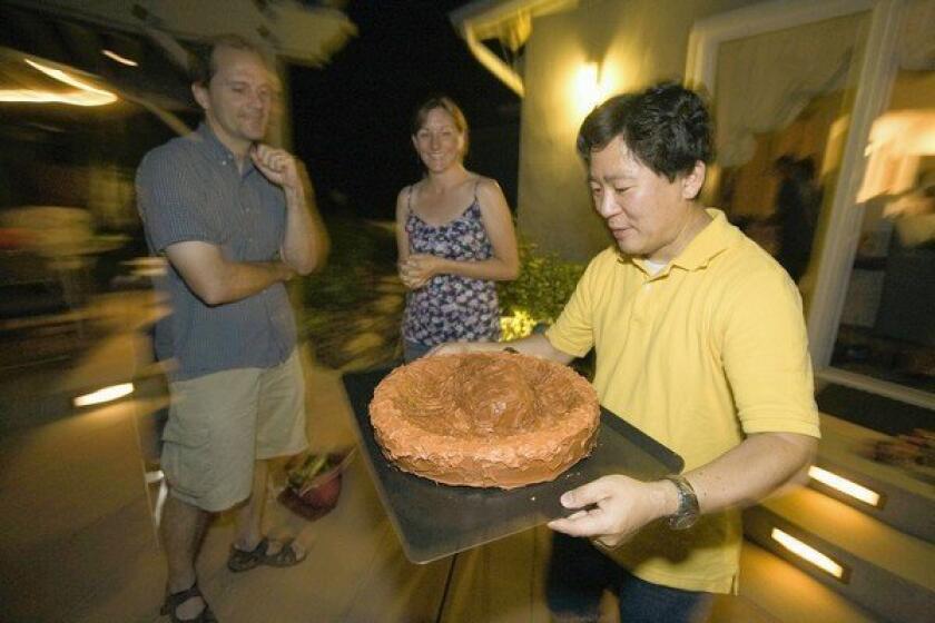 David Oh presents a Mars cake made by his wife, Bryn, during a late dinner on Mars time at their home in La Canada Flintridge.