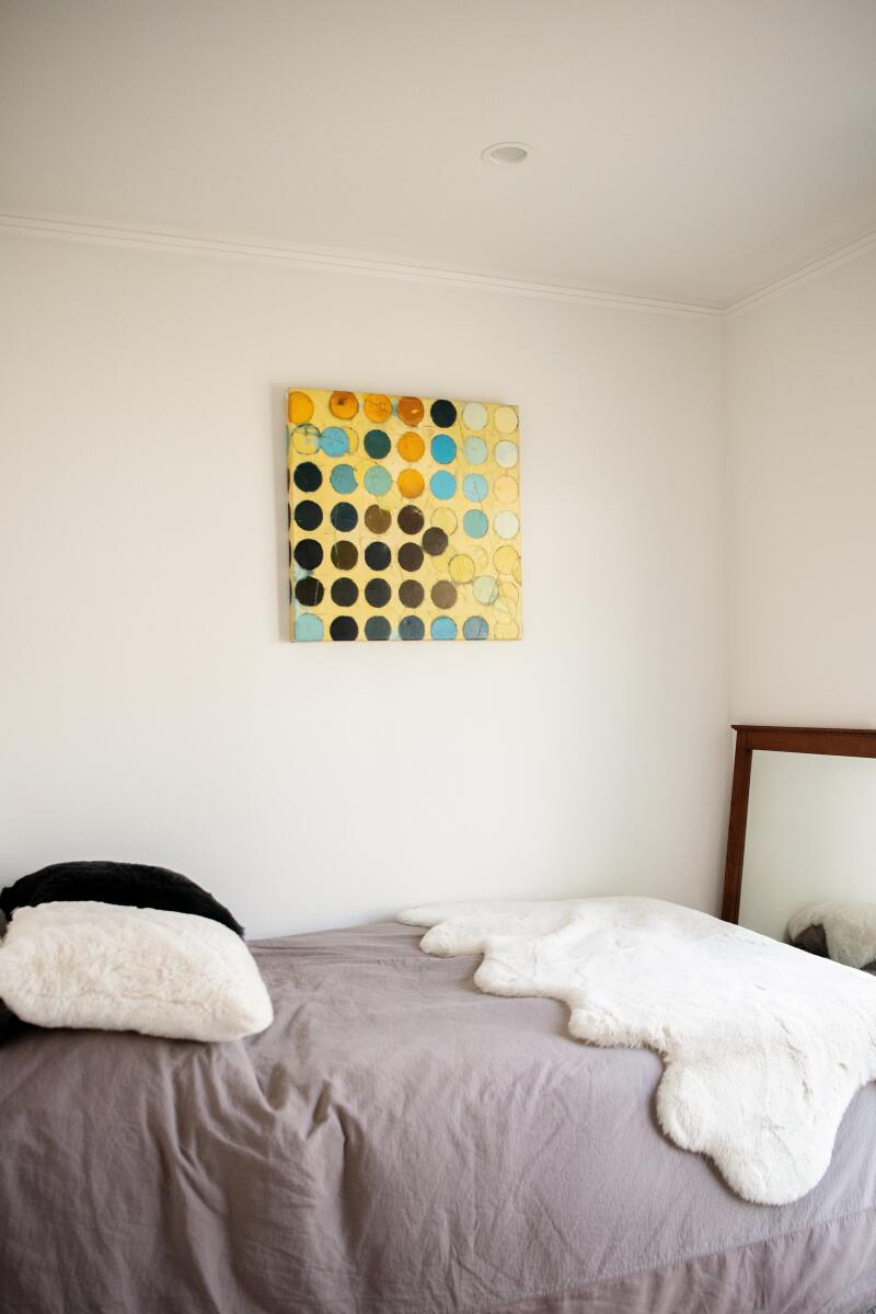 Artwork on the wall and gray and white bedding in a bedroom.