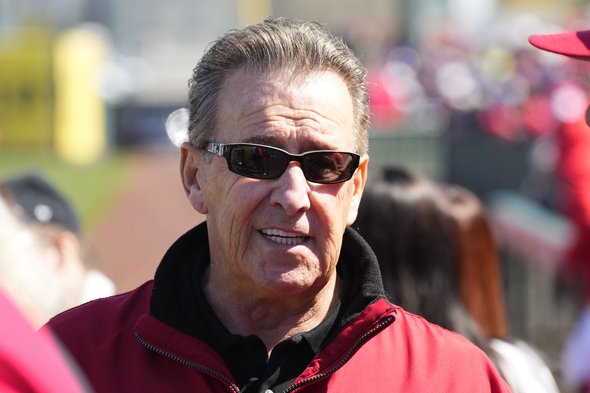 Angels owner Arte Moreno wearing sunglasses and a red zip-up jacket.