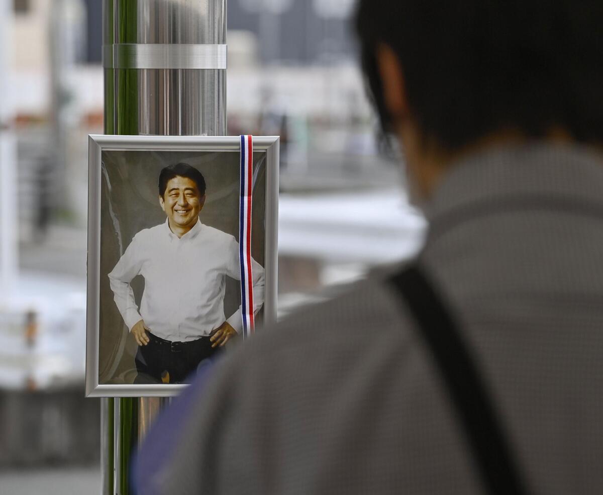A photo of former Japanese Prime Minister Shinzo Abe is displayed at a memorial area near the site where Abe was fatally shot in Nara, western Japan Friday, July 15, 2022. Many people mourned the death of Abe at the site where he was gunned down during a campaign speech a week ago Friday, shocking a nation known for its low crime rate and strict gun control. (Kyodo News via AP)