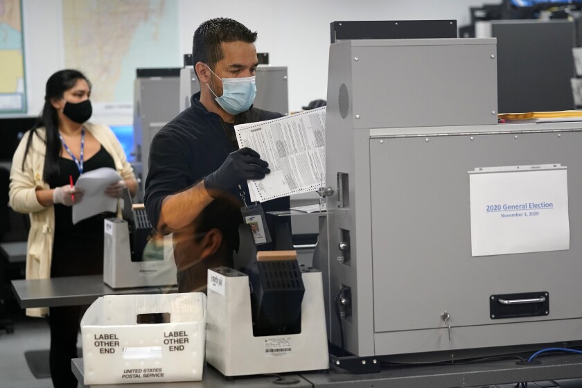 An election worker loads ballots into a scanning machine on Monday in Doral, Fla.