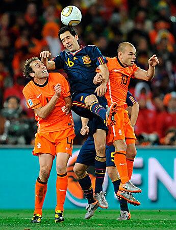 Spain's Sergio Busquets, center, and the Netherlands' John Mathijsen, left, and Wesley Sneijder hustle for the ball during the World Cup final match at Soccer City stadium in Johannesburg, South Africa.