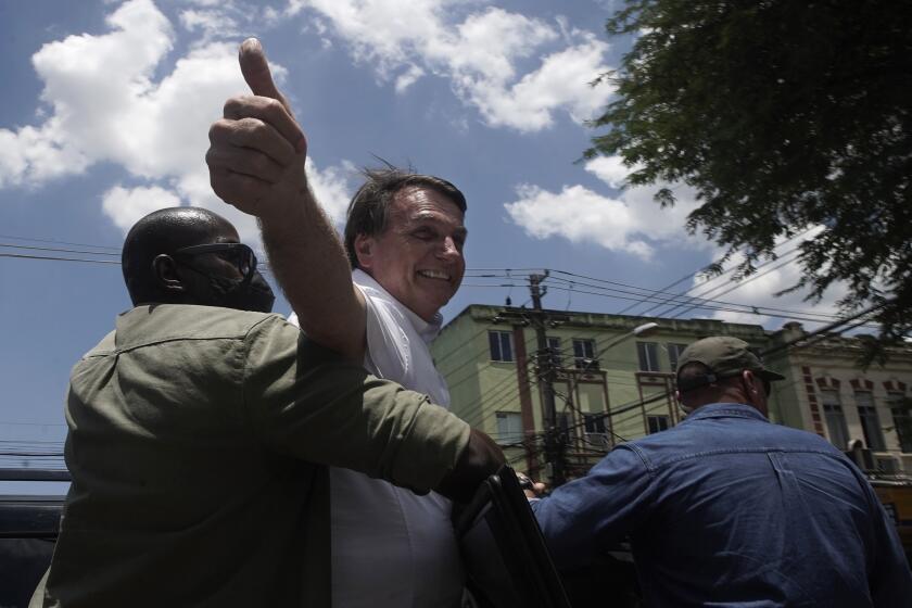Brazil's President Jair Bolsonaro greets supporters after voting during the run-off municipal elections in Rio de Janeiro, Brazil, Sunday, Nov. 29, 2020. Bolsonaro, who sometimes has embraced the label "Trump of the Tropics," said Sunday he'll wait a little longer before recognizing the U.S. election victory of Joe Biden, while also echoing President Donald Trump's allegations of irregularities in the U.S. vote. (AP Photo/Silvia Izquierdo)
