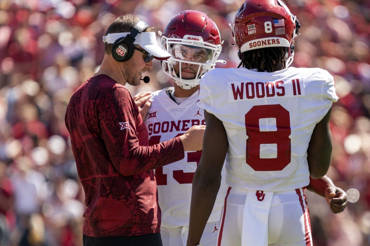 Lincoln Riley, left, talks with quarterback Caleb Williams, center, and wide receiver Michael Woods II.