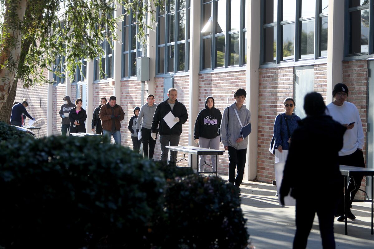 Parents and students wait to pick up loaner laptops from school staff at Hoover High School in Glendale on Thursday.
