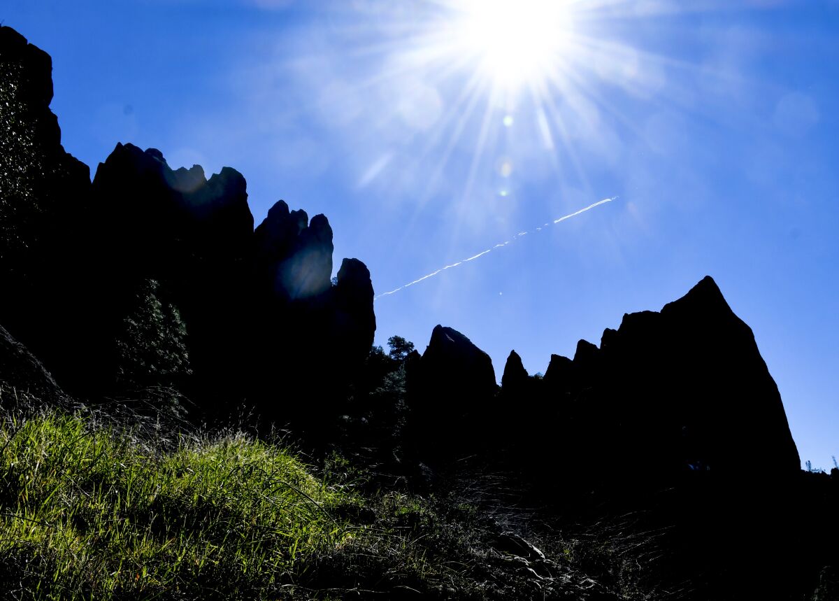 Rocks in silhouette beneath a blazing sun
