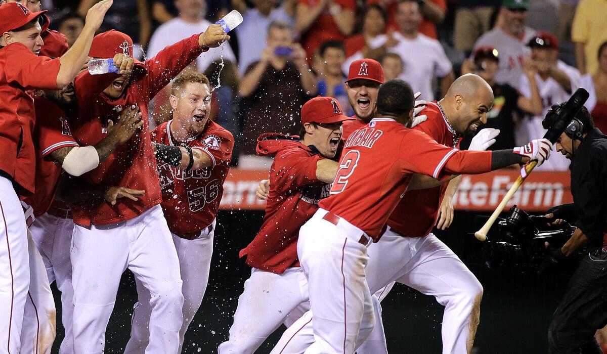 Angels teammates chase after Albert Pujols, right, after he slid into home plate and tried to run away following his game-winning home run against the Red Sox early Sunday morning.