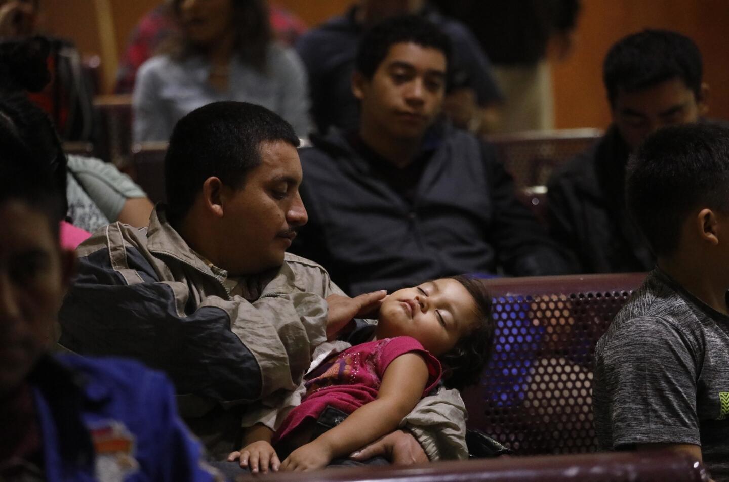 MCALLEN, TX - APRIL 3, 2019 - - Eulogio Erazo Varela, 28, from Honduras, comforts his ill daughter Kimberlin Erazo, 3, while joining recently released migrants who wait to catch a bus at the McAllen Central Station in McAllen, Texas on April 3, 2019. Varela was planning to travel to Memphis, Tenn. to stay with a friend. Migrants, recently released from custody, travel by bus or airplane to stay with relatives and friends in the United States. Volunteers from Angry Tias and Abuelas, Catholic Charities, and local churches find new challenges with the expected release in the coming days of some 5,600 immigrants in McAllen, Brownsville and Harlingen, Texas. (Genaro Molina/Los Angeles Times)